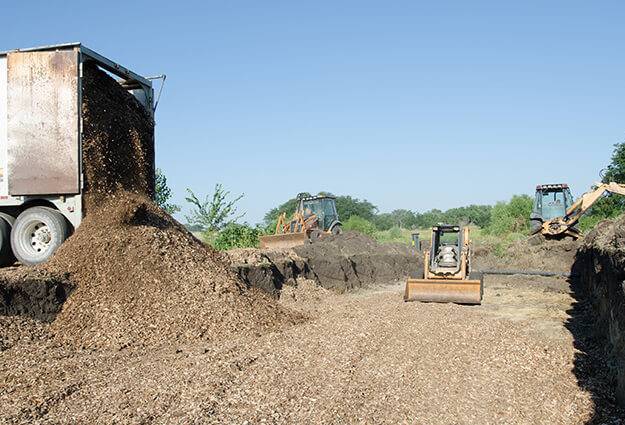 mound of wood mulch with heavy equipment