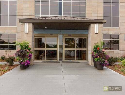 spring containers with purple and pink florals located in front of an office building