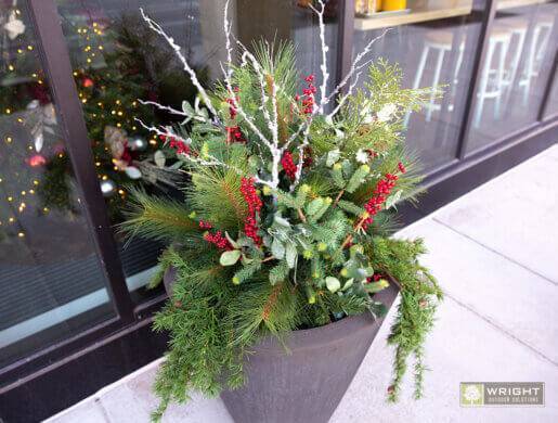 winter greens with red berries and white twigs located in front of an office building