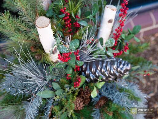 winter greens with red berries, pinecones, and birch logs